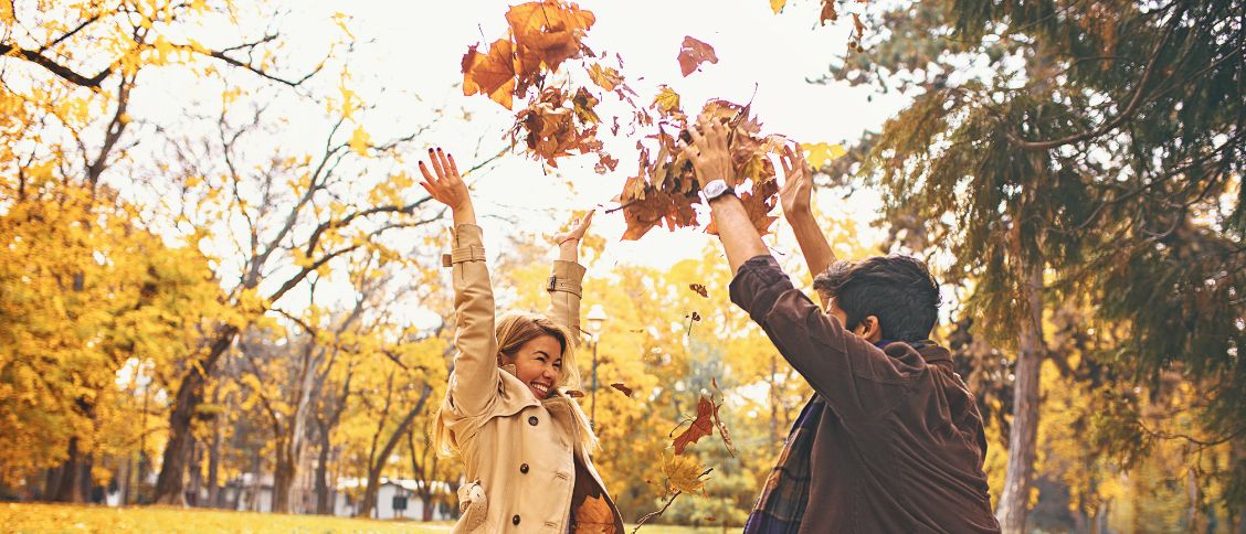 couple in fall throwing leafs